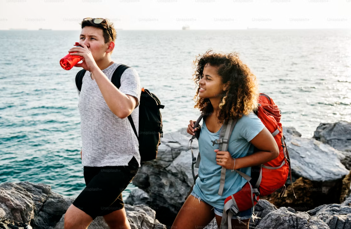 Travelers drinking water by the sea during an active day
