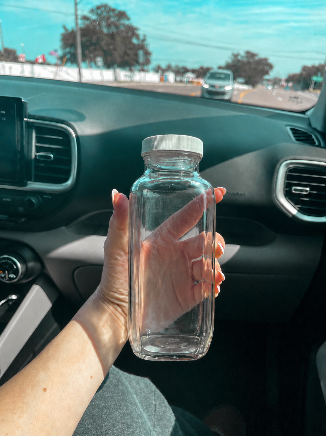 Clear light protein bottle held in a car